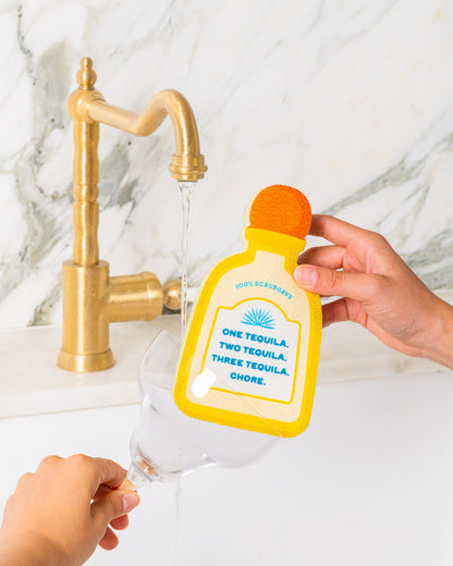 funny tequila shaped yellow kitchen sponge washing margarita glass in kitchen sink