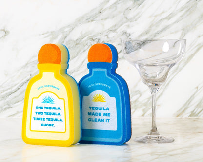 Two novelty tequila bottle-shaped sponges on a marble surface with a glass next to clean margarita glass