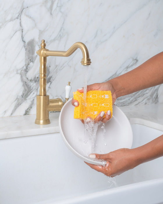 squeezing sponge with water in kitchen sink