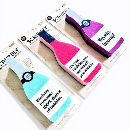Scrubbly bottle-shaped sponges with humorous text on a white background celebration birthday pink teal purple hooray