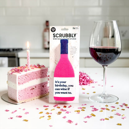 Scrubbly wine bottle cleaning sponge pink with a cake and wine glass on a table.