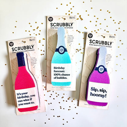 Three Scrubbly wine wash kitchen sponges in their packaging with celebratory text on a white background with confetti party favor
